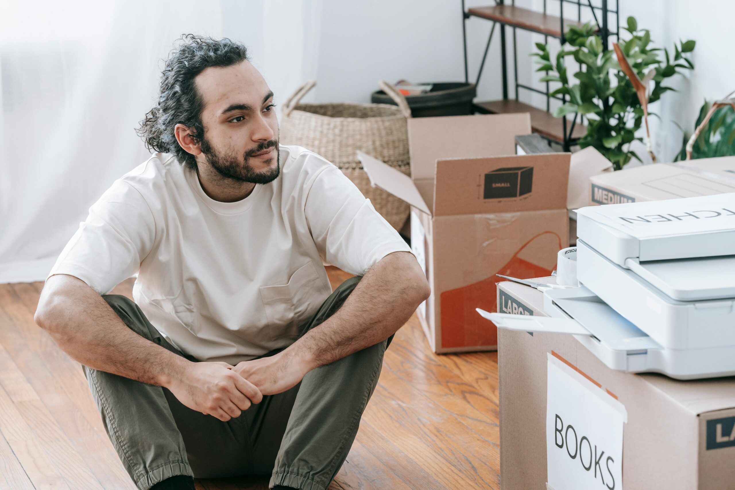 man sitting thoughtfully by packed boxes