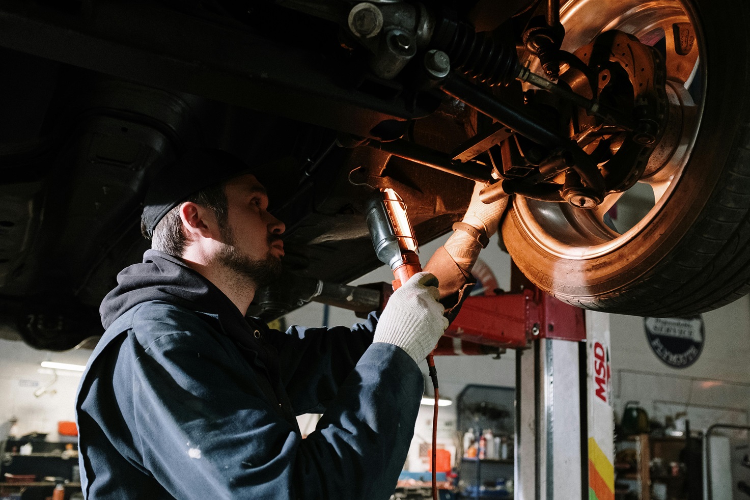 man working under car looking at brakes