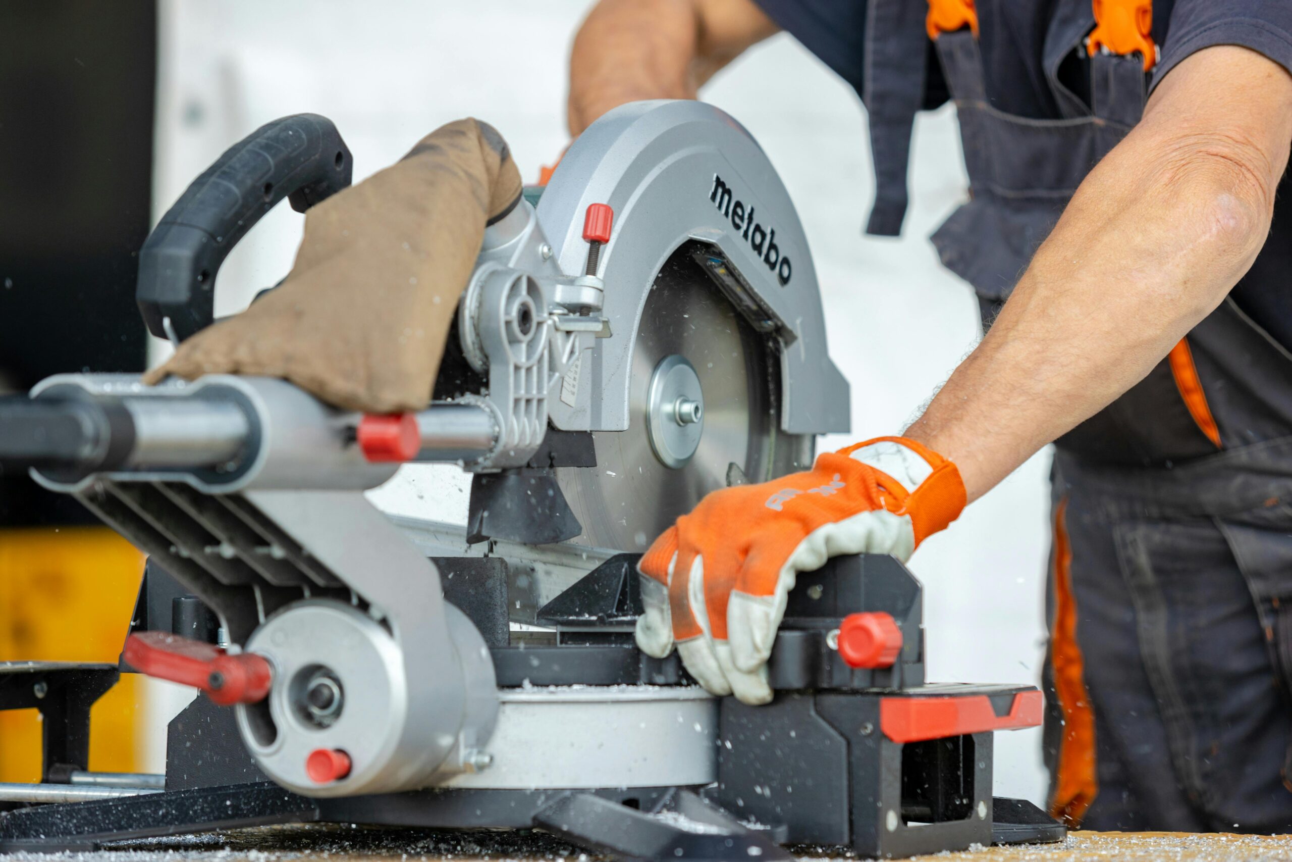 man using a circular saw with gloves