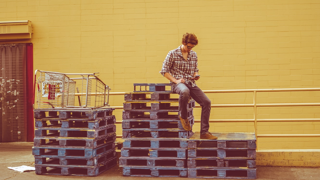 man sitting on a stack of pallets
