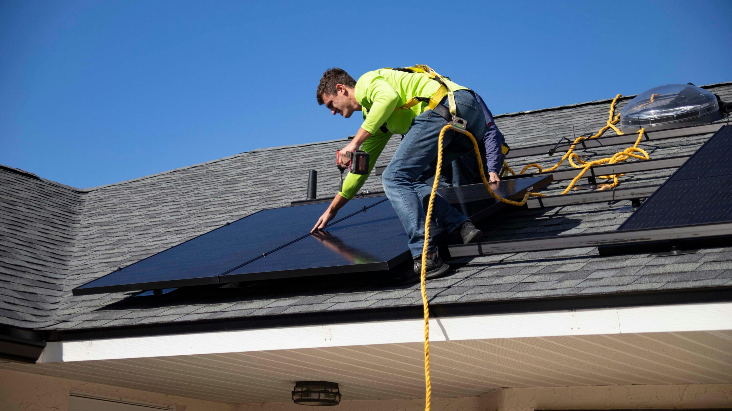 man installing solar panels on roof
